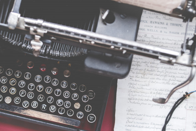 closeup-shot-old-vintage-typewriter-red-desk-with-paper-side_181624-3856